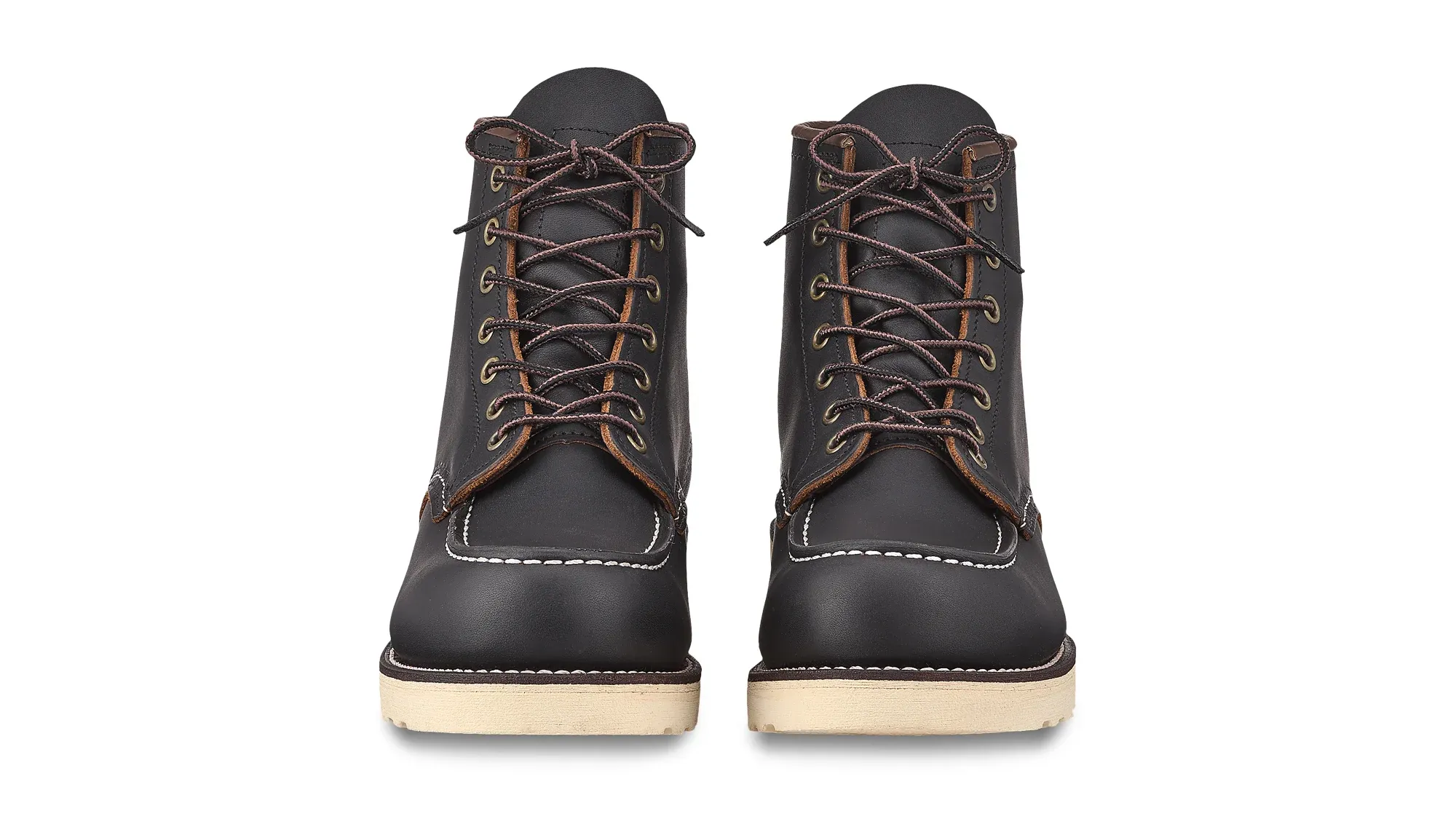 A pair of black leather moc toe boots on cream wedge soles, seen straight on from the front