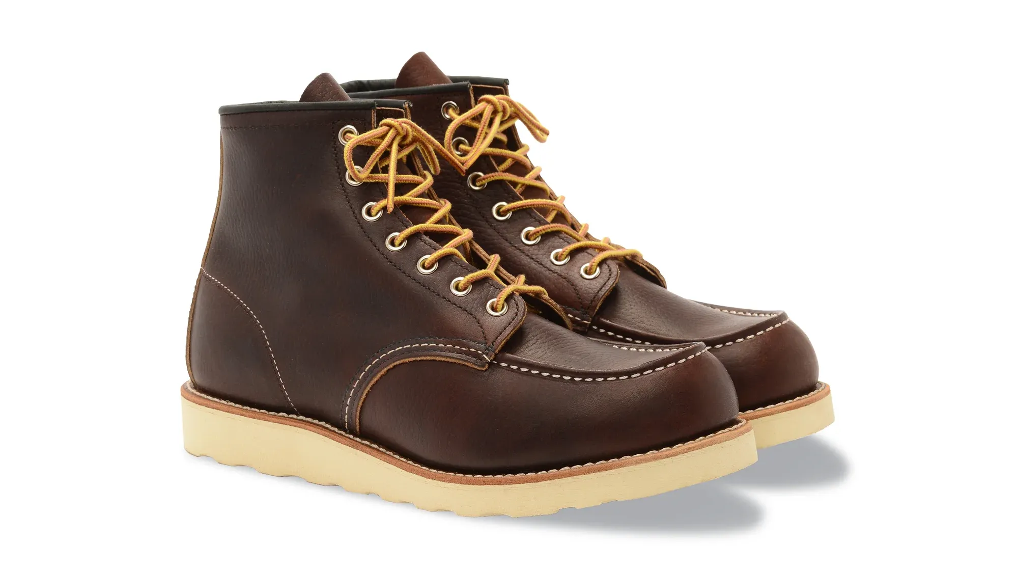 A pair of dark brown leather moc toe boots on cream wedge soles, seen from the front at an angle