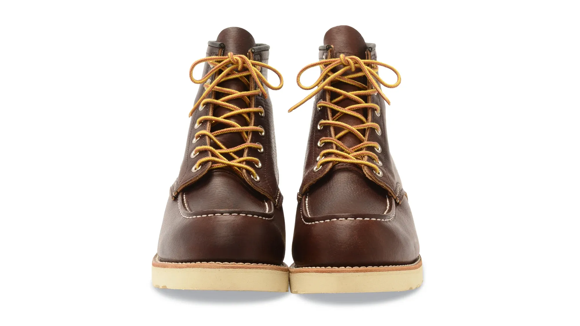 A pair of dark brown leather moc toe boots on cream wedge soles, seen straight on from the front