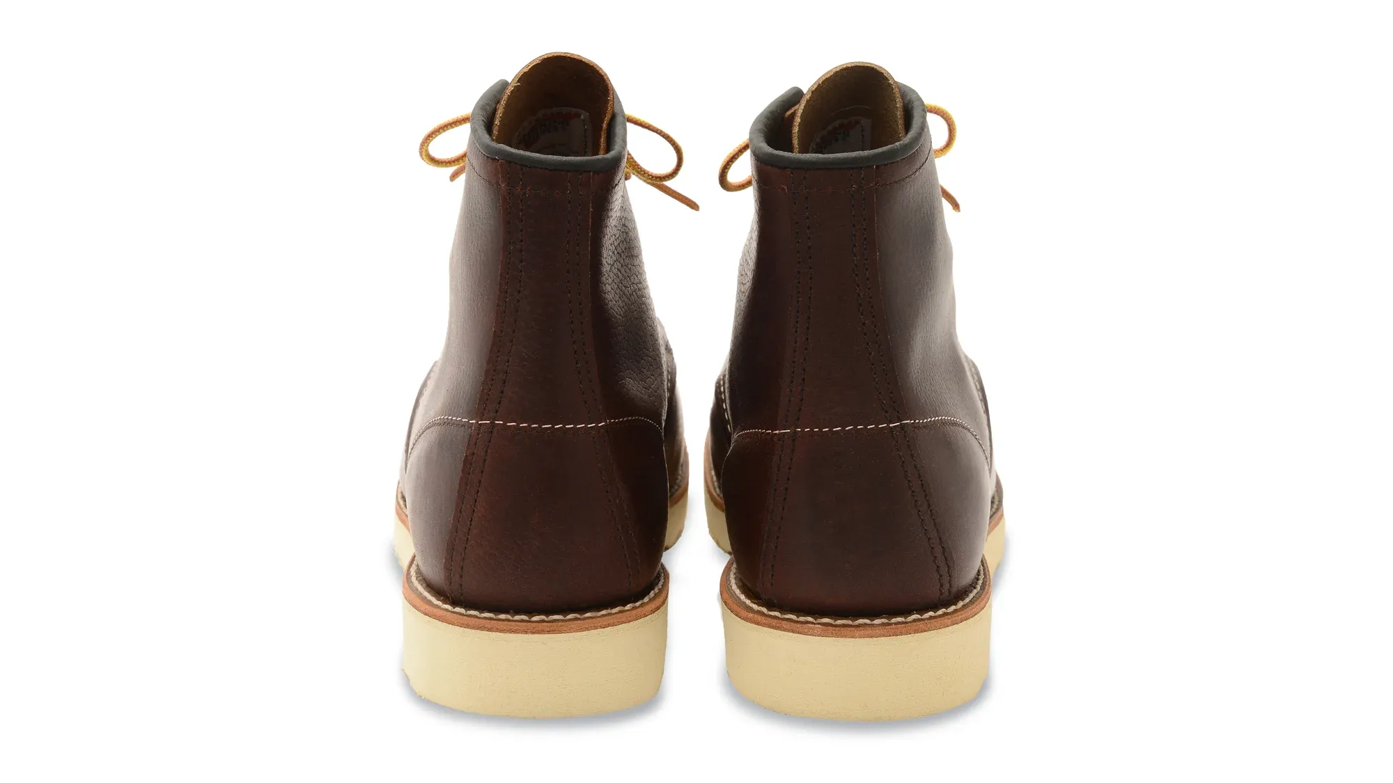 A pair of dark brown leather moc toe boots on cream wedge soles, seen straight on from the heels