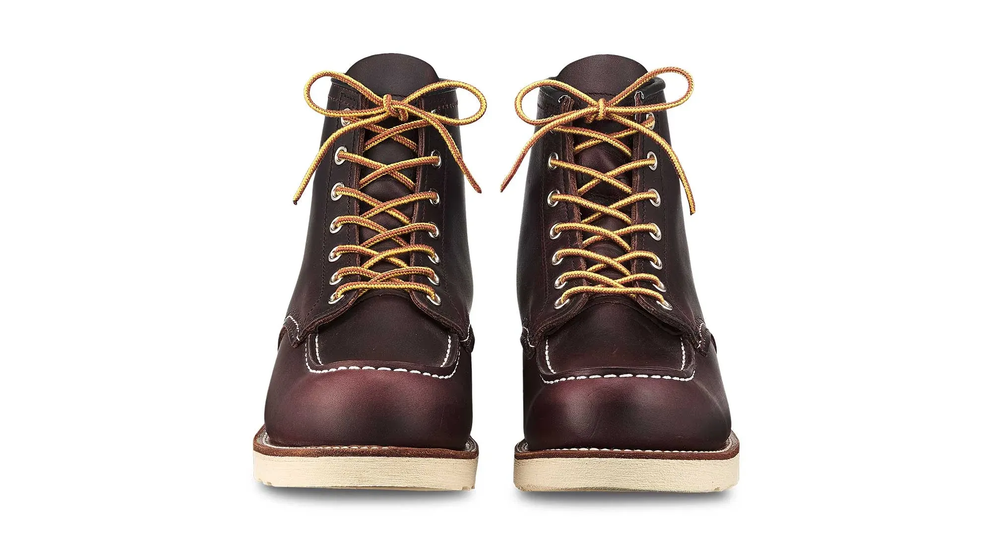 A pair of oxblood leather moc toe boots on cream wedge soles, seen straight on from the front