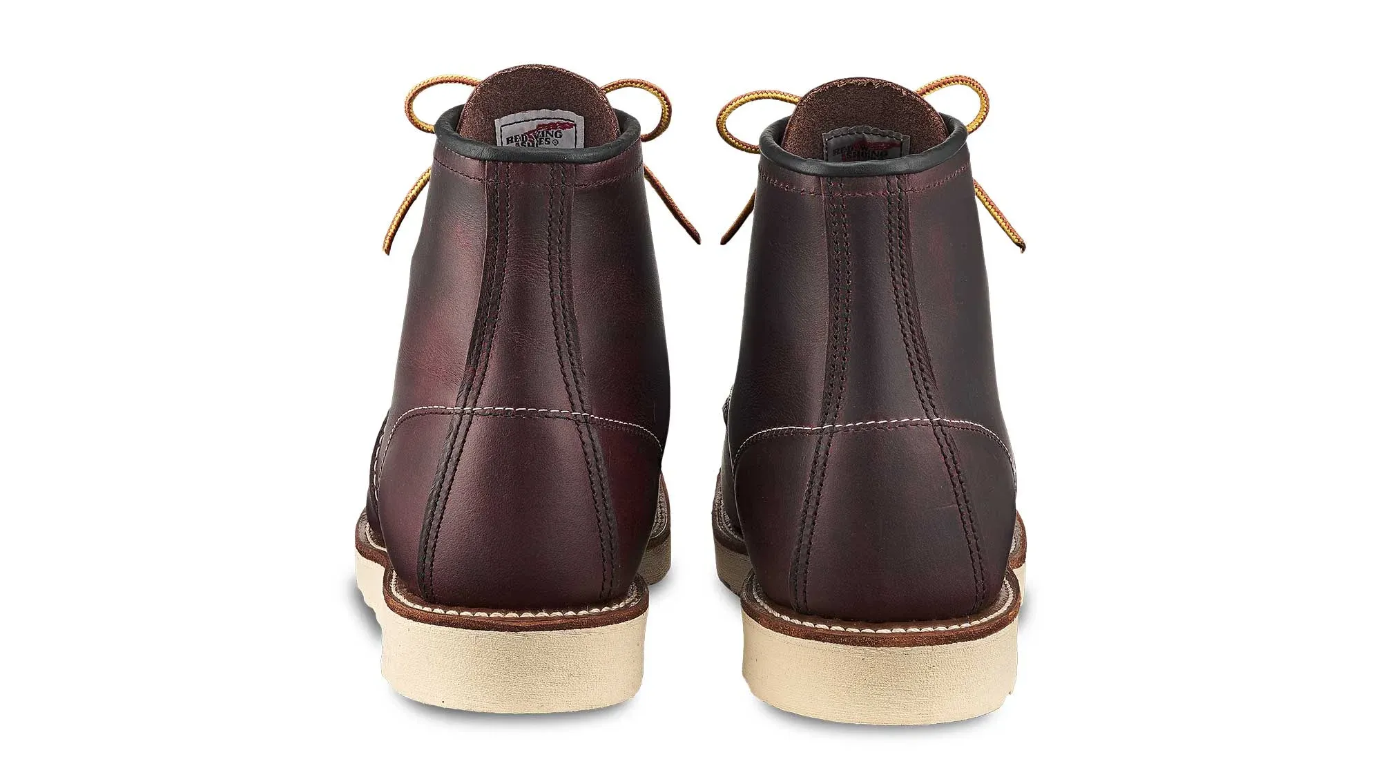 A pair of oxblood leather moc toe boots on cream wedge soles, seen straight on from the heels