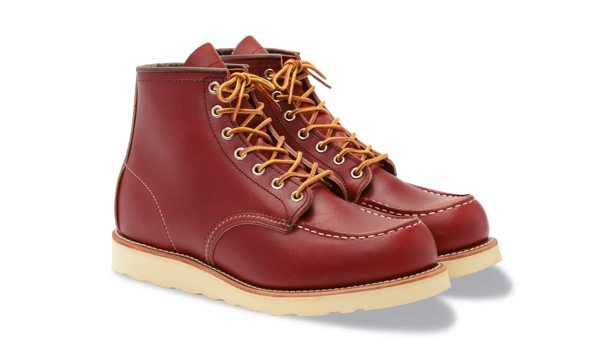 A pair of red leather moc toe boots on cream wedge soles, seen from the front at an angle