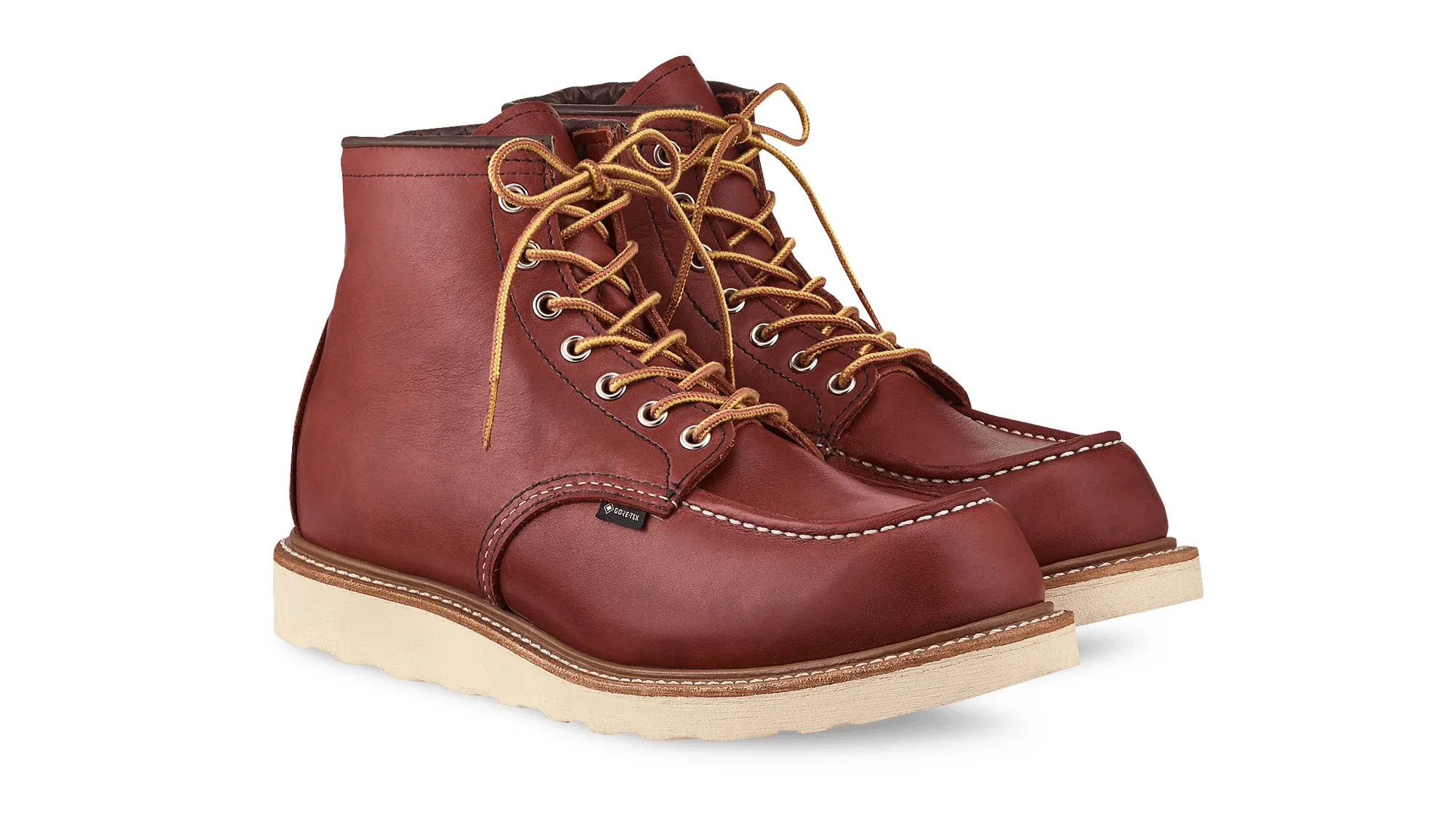 A pair of russet leather moc toe boots on cream wedge soles, seen from the front at an angle