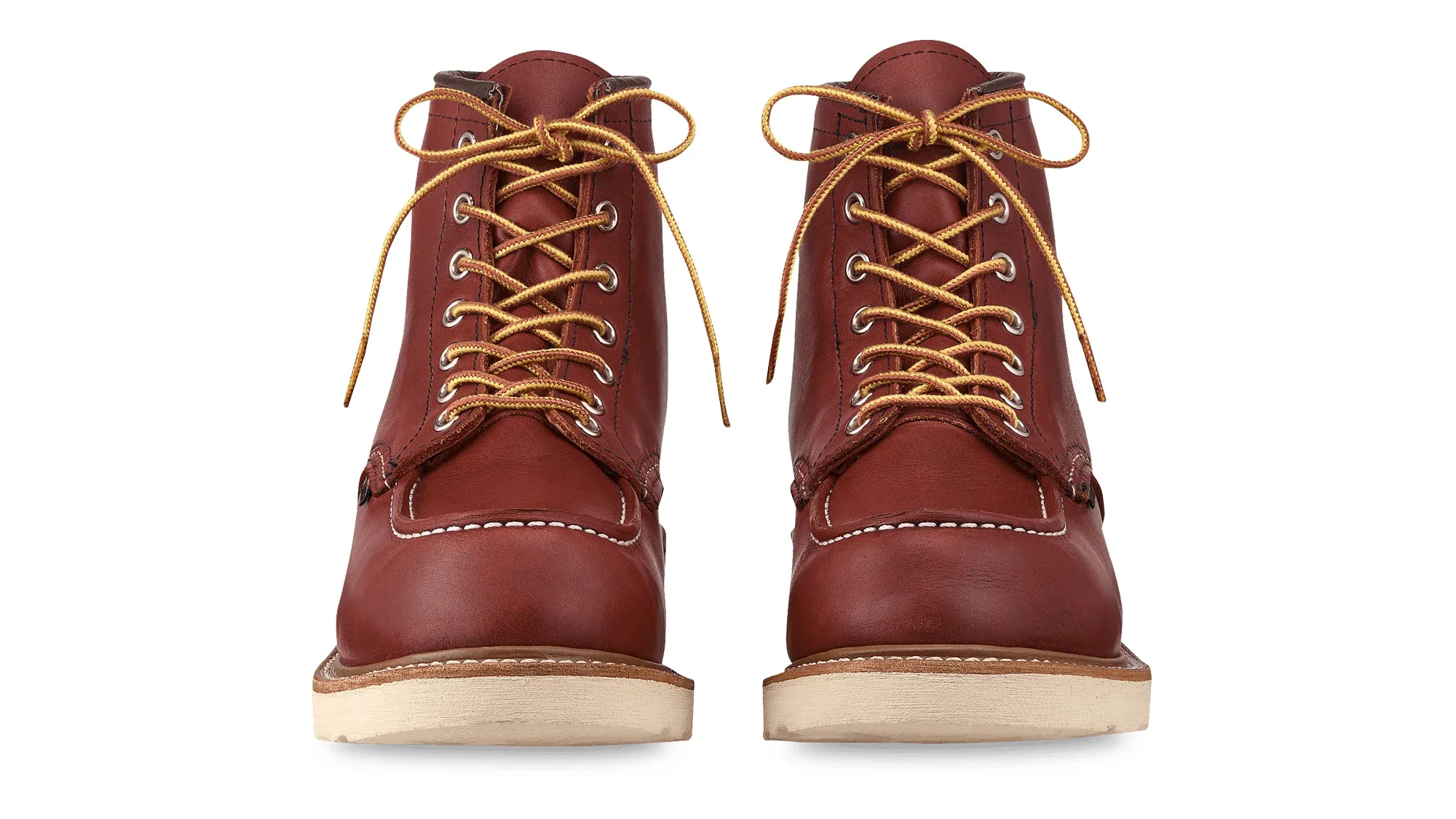 A pair of russet leather moc toe boots on cream wedge soles, seen straight on from the front