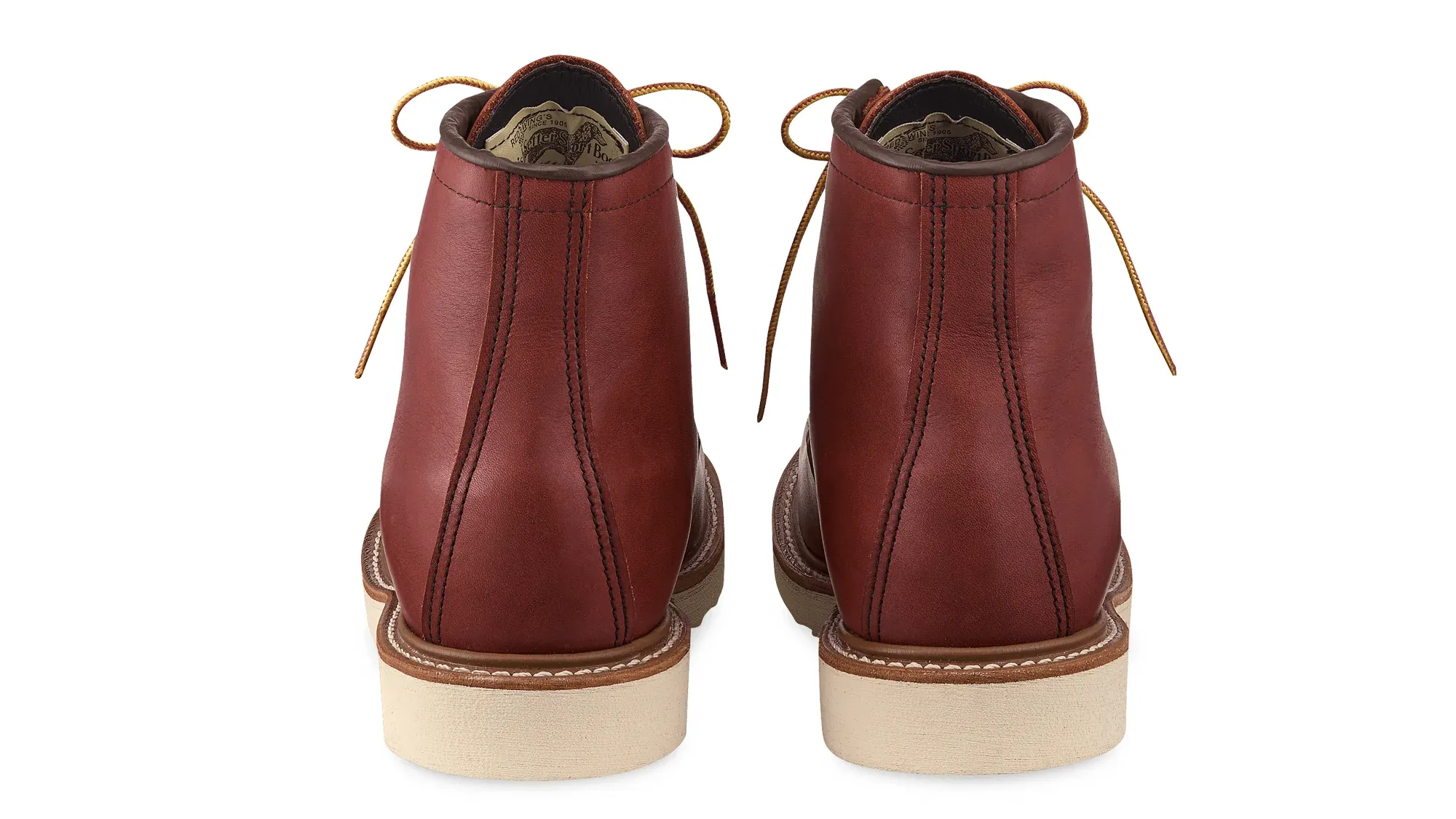 A pair of russet leather moc toe boots on cream wedge soles, seen straight on from the heels