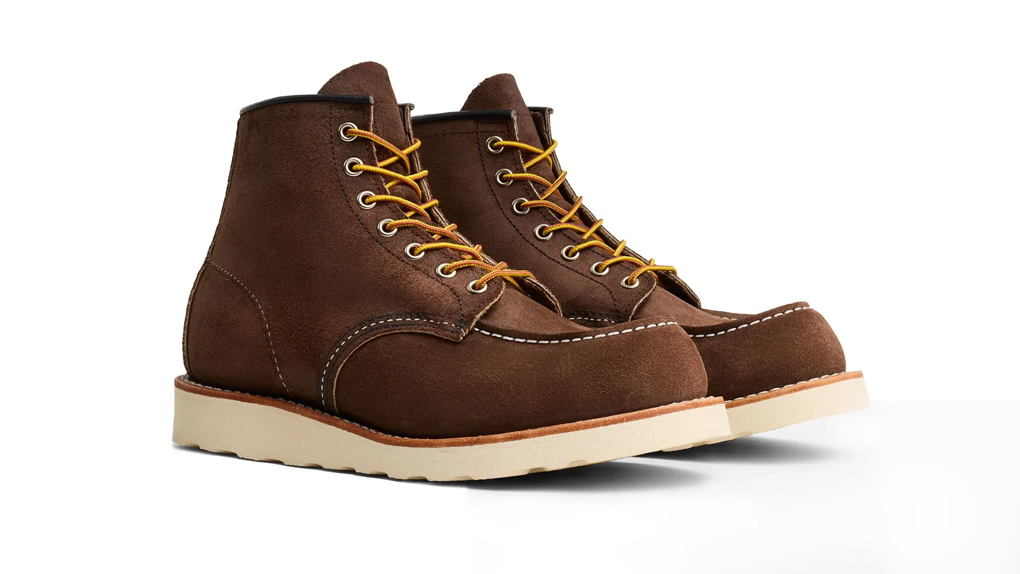 A pair of chocolate roughout suede moc toe boots on cream wedge soles, seen from the front at an angle