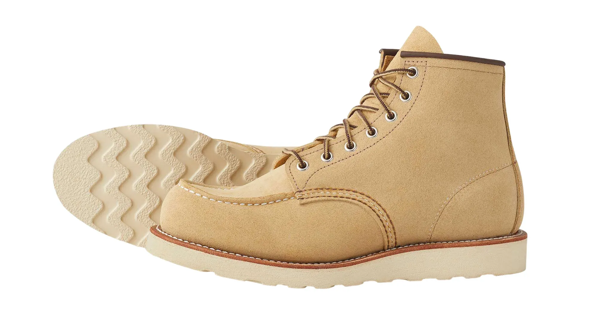 A sand roughout suede moc toe boot on a cream wedge sole, tipped on its side to show the sole