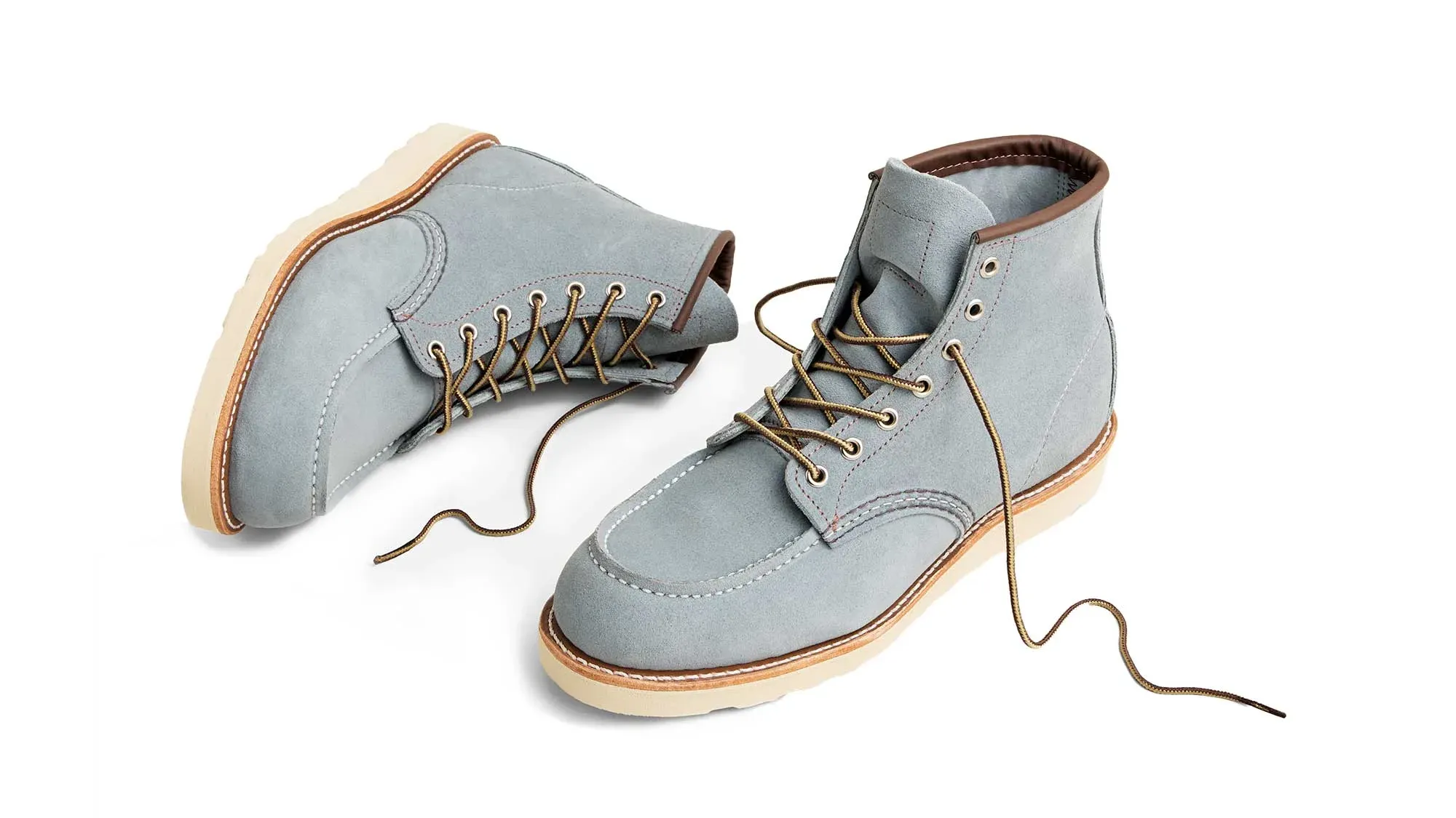 A pair of sky roughout suede moc toe boots on cream wedge soles, lying on their sides with the laces undone