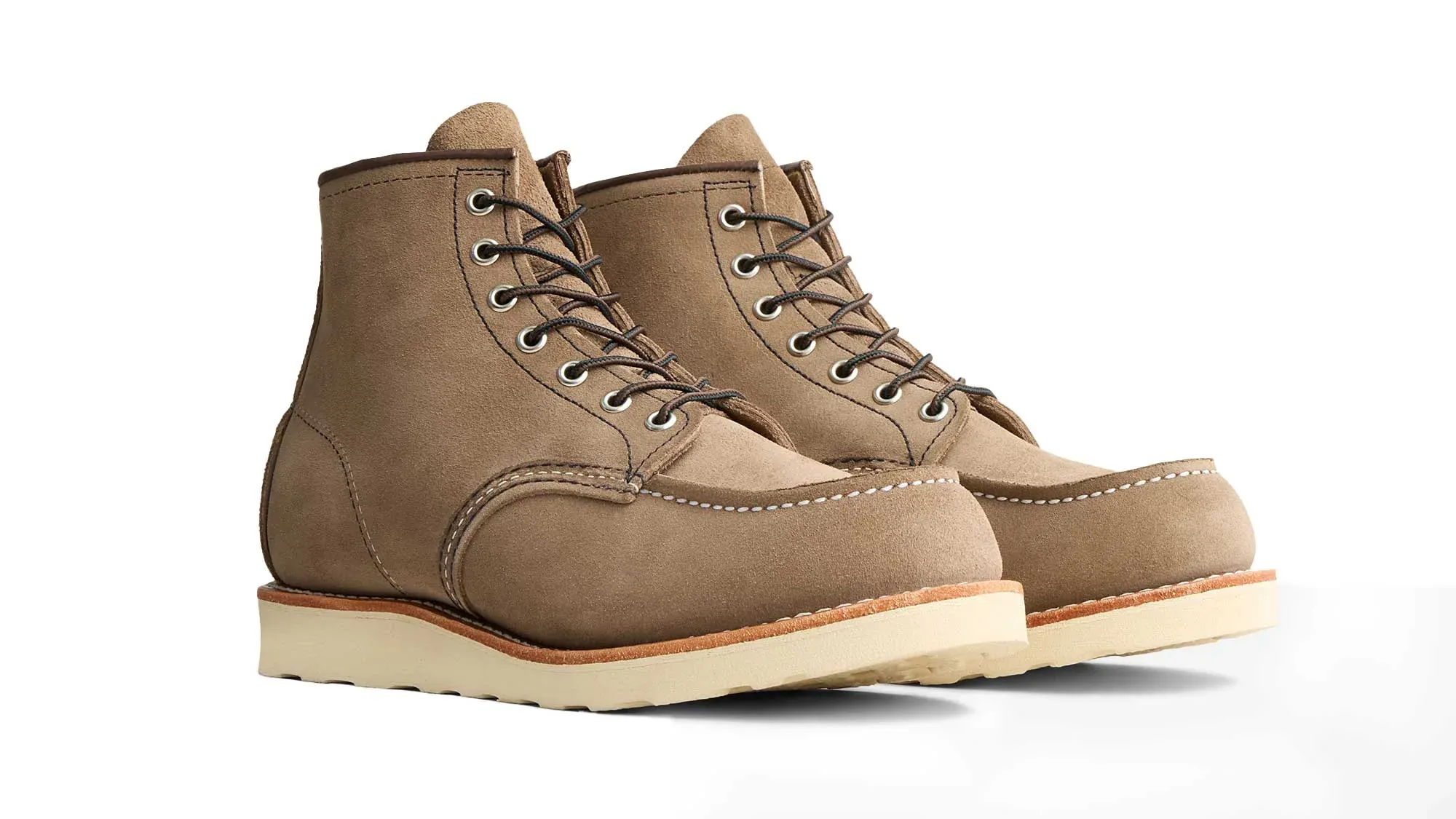 A pair of taupe roughout suede moc toe boots on cream wedge soles, seen from the front at an angle