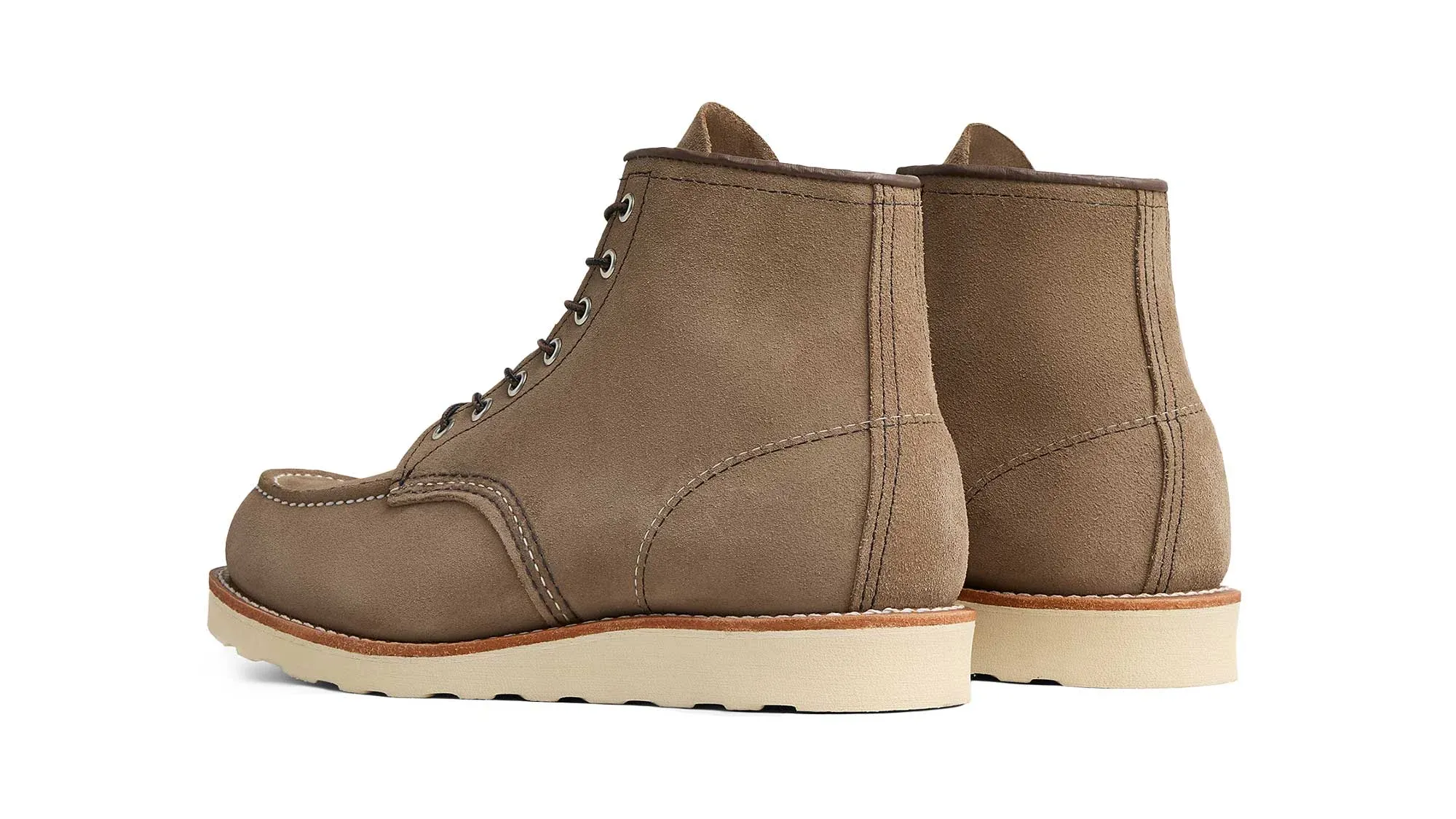 A pair of taupe roughout suede moc toe boots on cream wedge soles, seen from behind at an angle