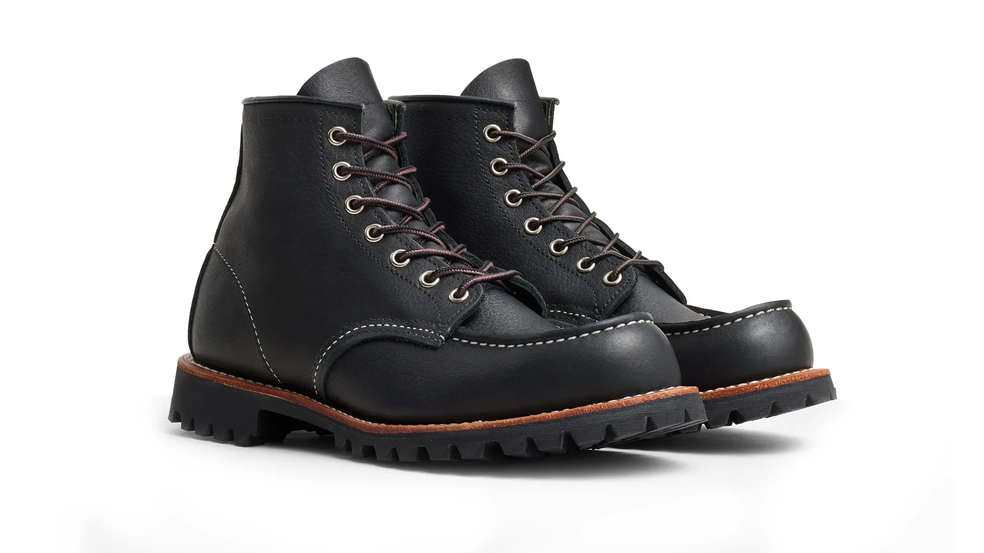 A pair of black leather moc toe boots on black lug soles, seen from the front at an angle
