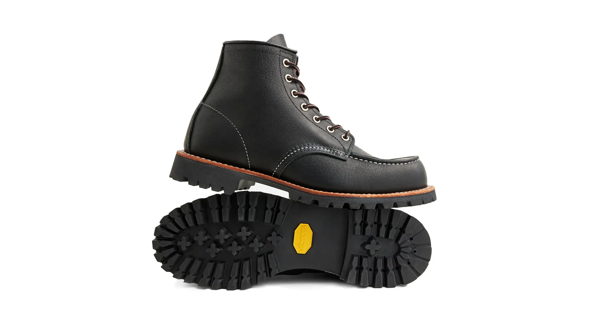 A black leather moc toe boot on a black lug sole, tipped on its side to show the sole