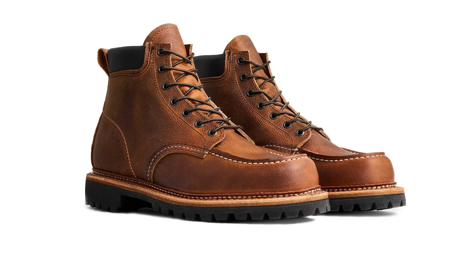 A pair of brown leather moc toe boots on black lug soles, seen from the front at an angle
