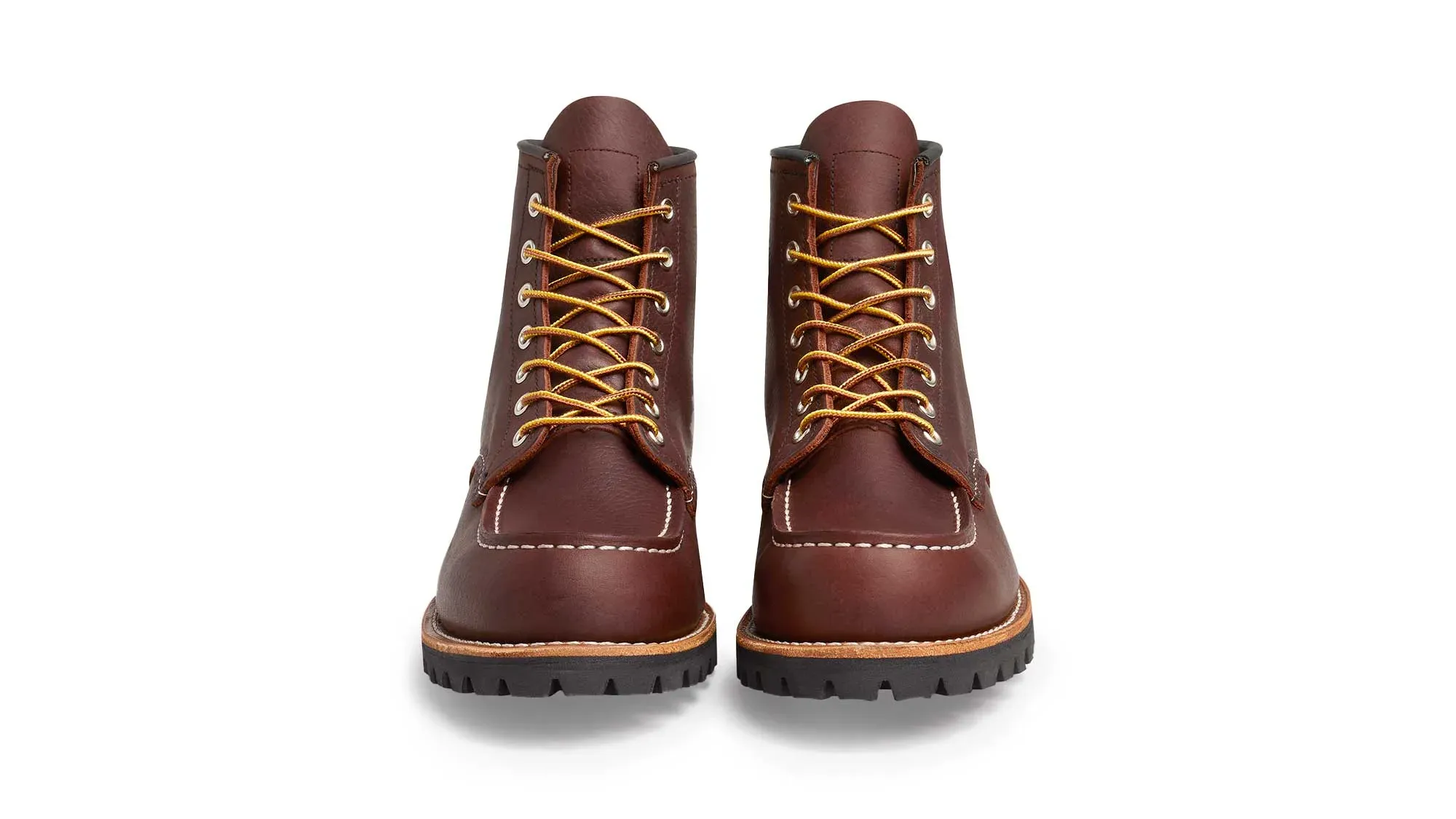 A pair of oxblood leather moc toe boots on black lug soles, seen straight on from the front