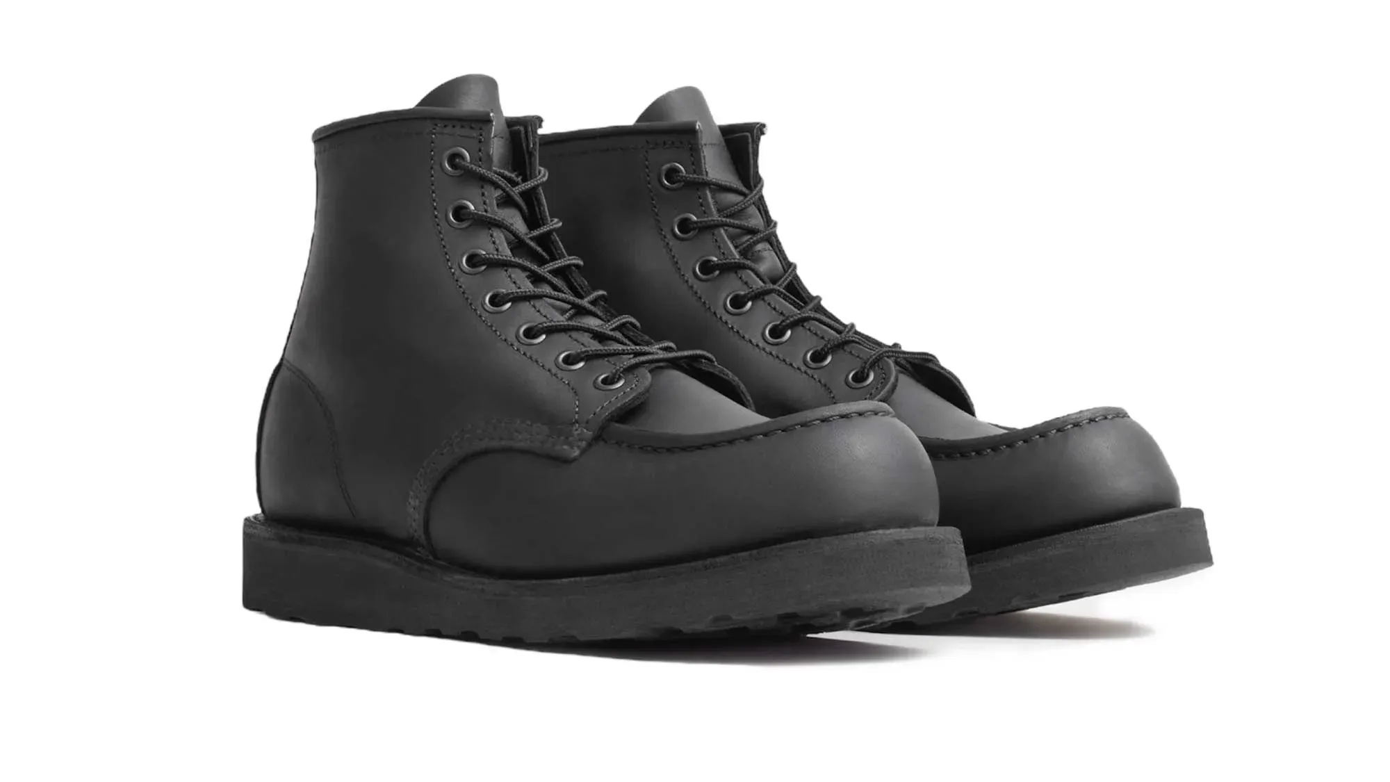 A pair of black waxed suede moc toe boots on black lug soles, seen from the front at an angle