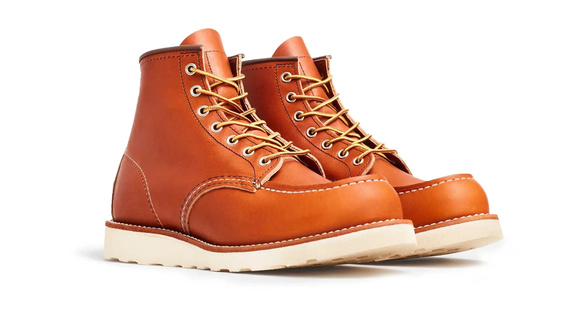 A pair of amber leather moc toe boots on cream wedge soles, seen from the front at an angle