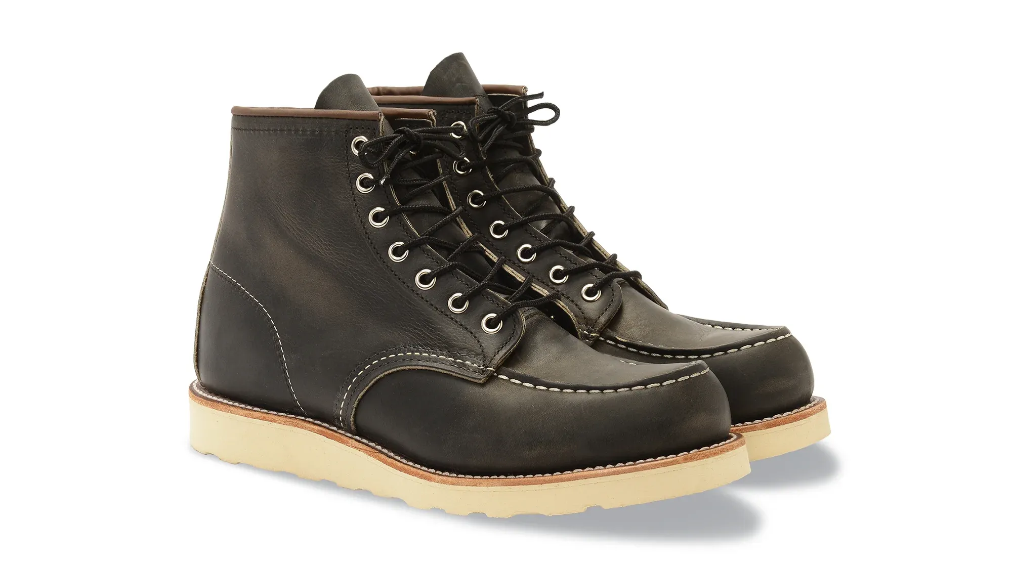A pair of charcoal leather moc toe boots on cream wedge soles, seen from the front at an angle