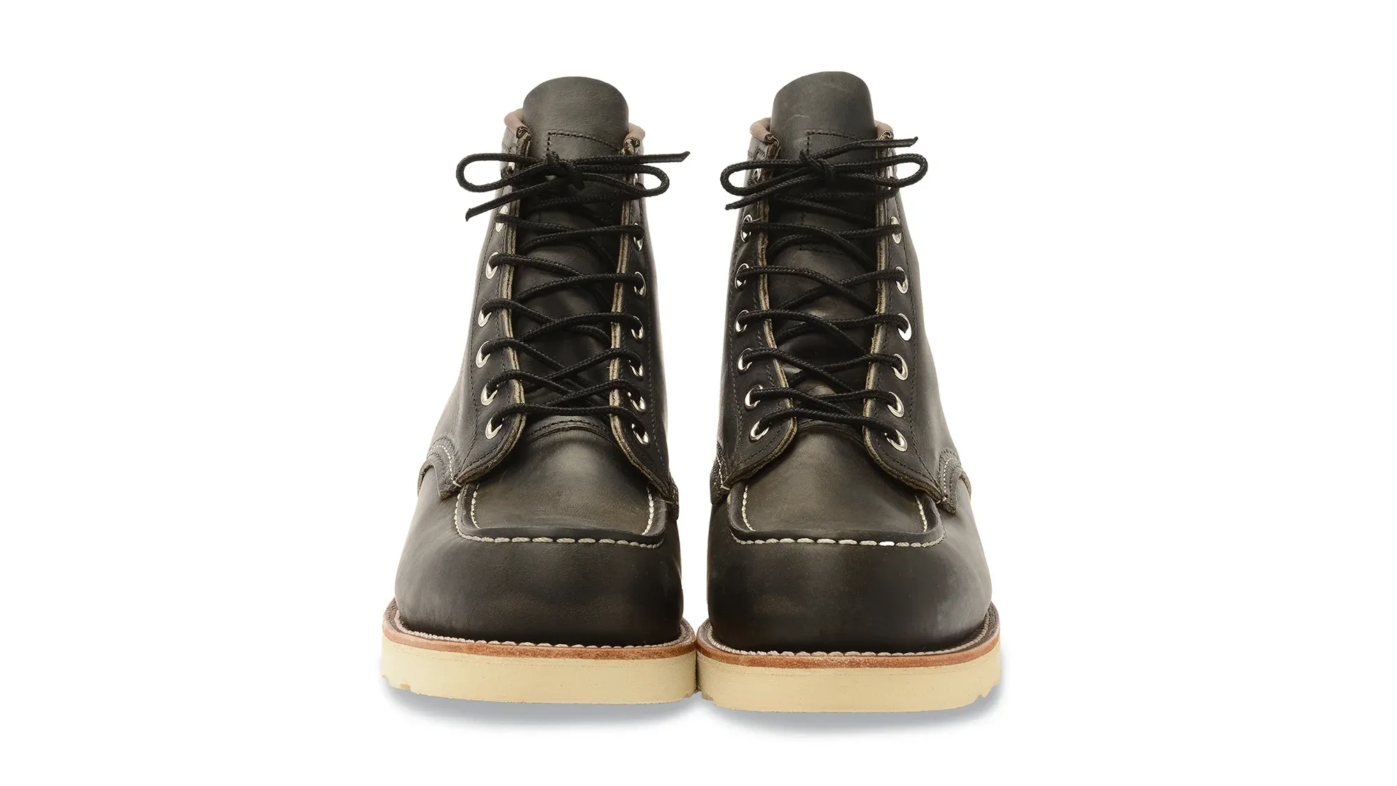 A pair of charcoal leather moc toe boots on cream wedge soles, seen straight on from the front