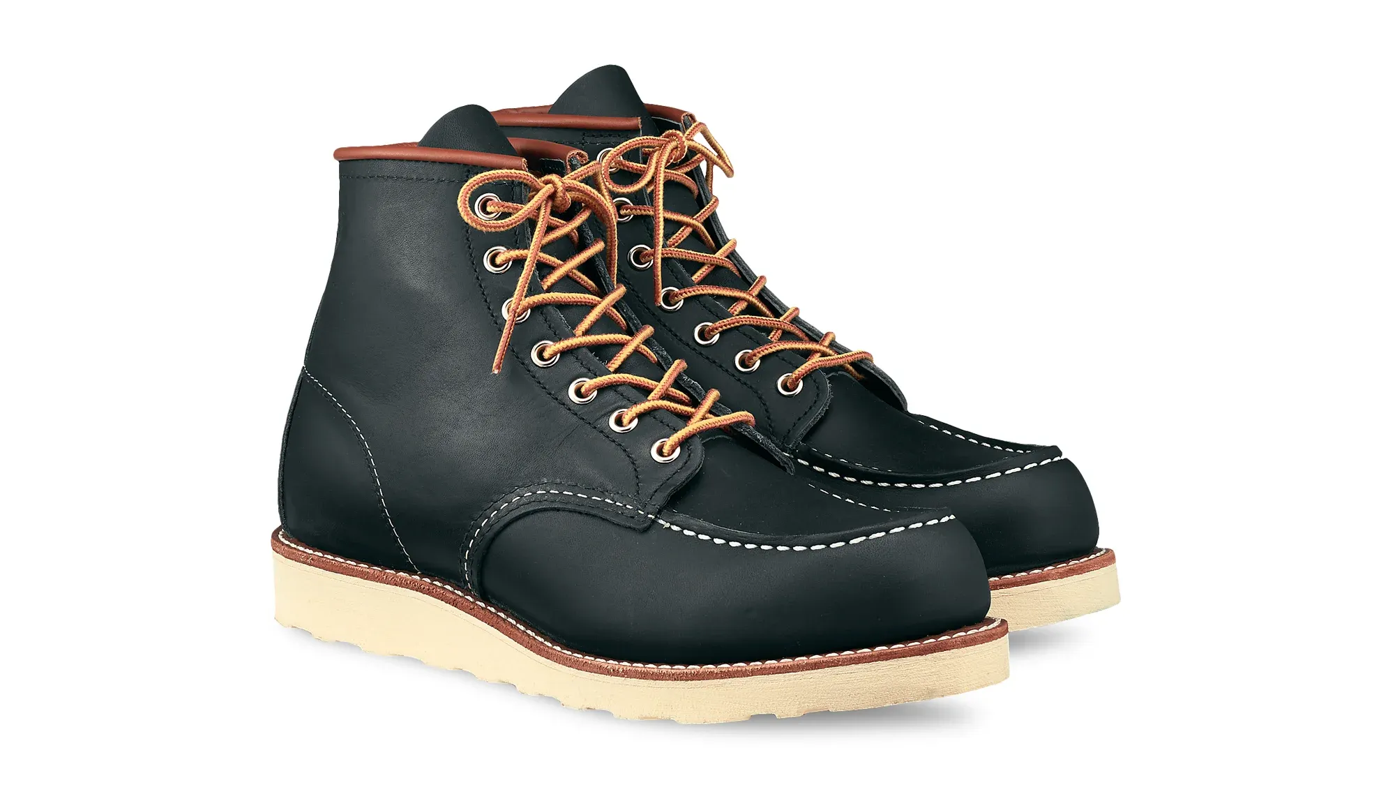 A pair of navy leather moc toe boots on cream wedge soles, seen from the front at an angle
