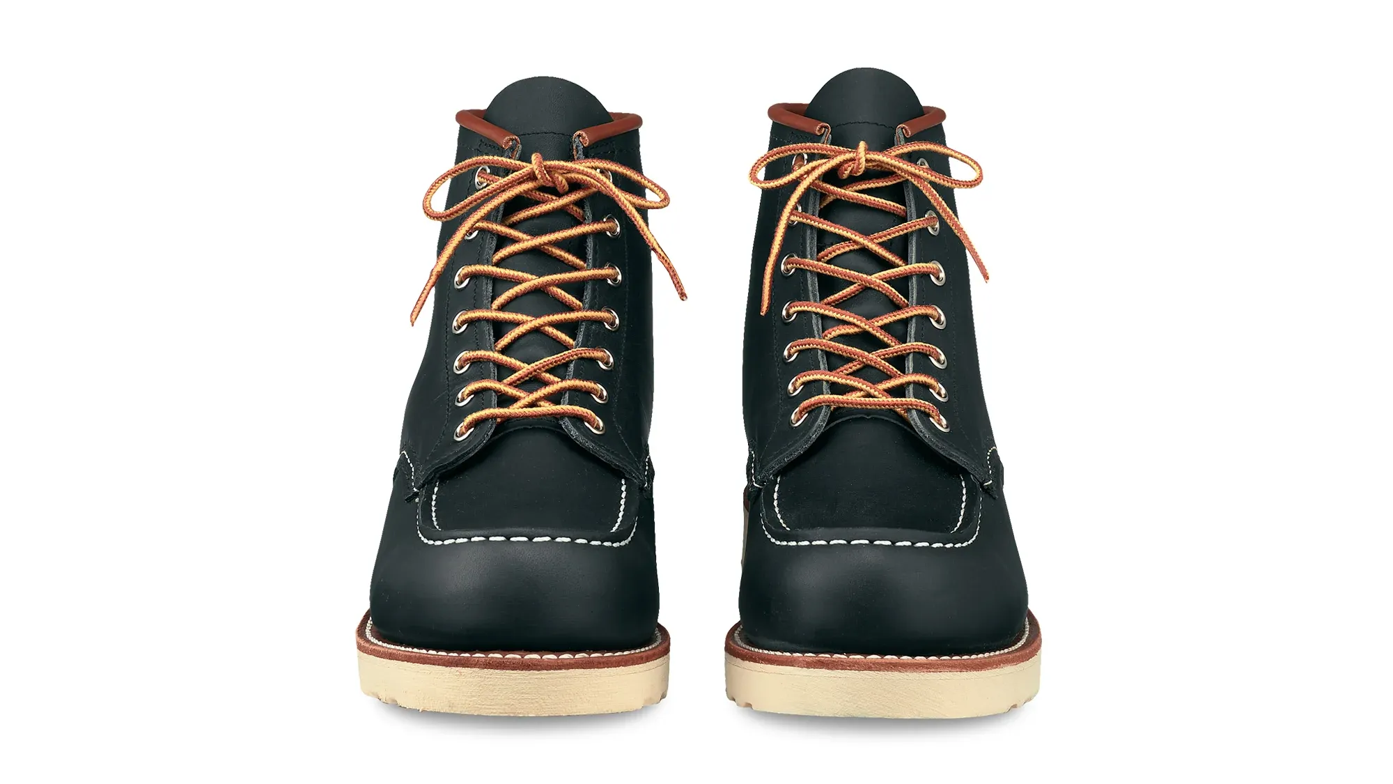 A pair of navy leather moc toe boots on cream wedge soles, seen straight on from the front
