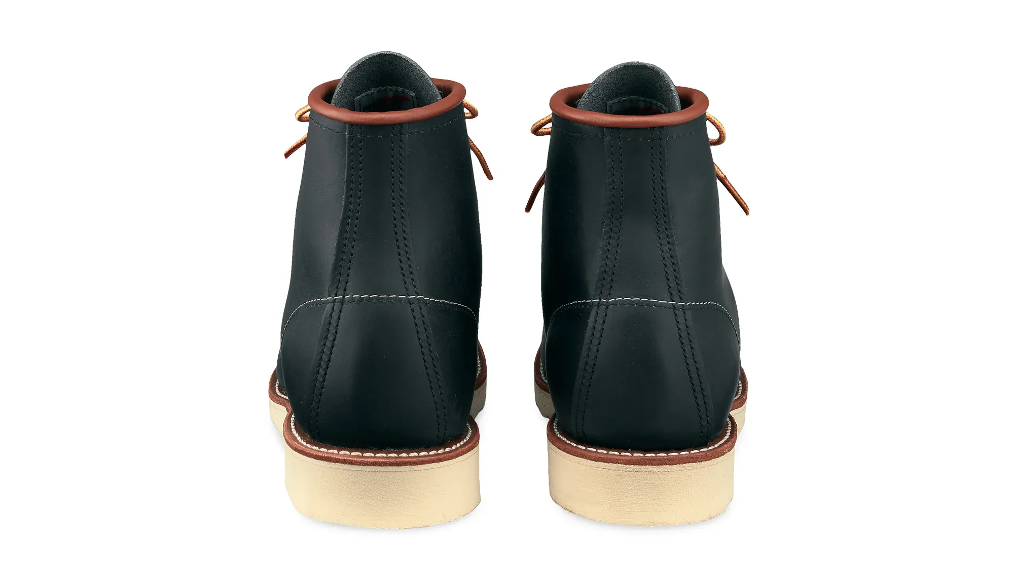A pair of navy leather moc toe boots on cream wedge soles, seen straight on from the heels